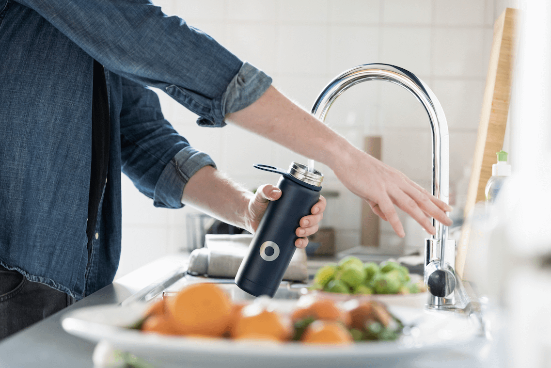 Someone fillinf up their water bottle from a tap